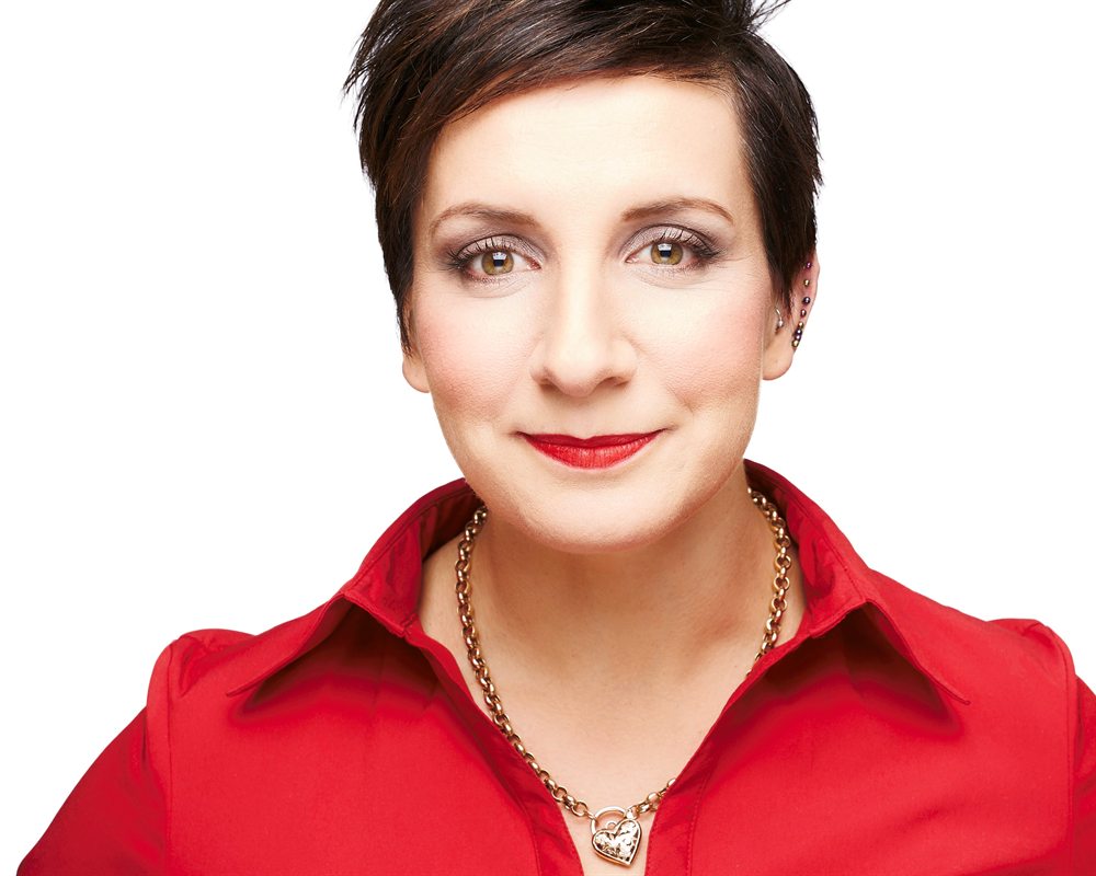 Portrait of Naomi Malouf, smiling, wearing a red shirt